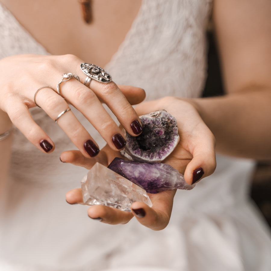 Hands with silver rings holding amethyst and quartz crystals