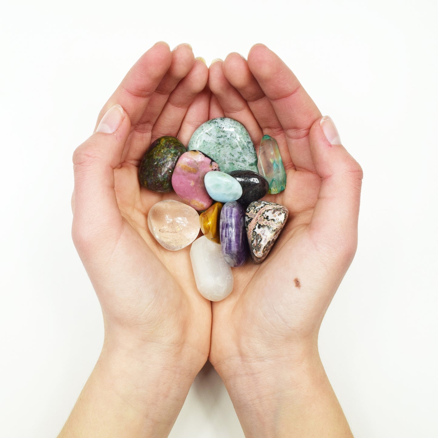 Hands holding colorful gemstones and crystals.