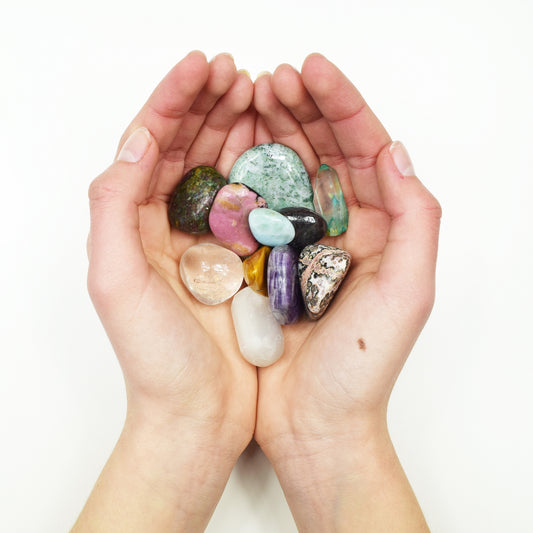 Hands holding colorful gemstones and crystals.