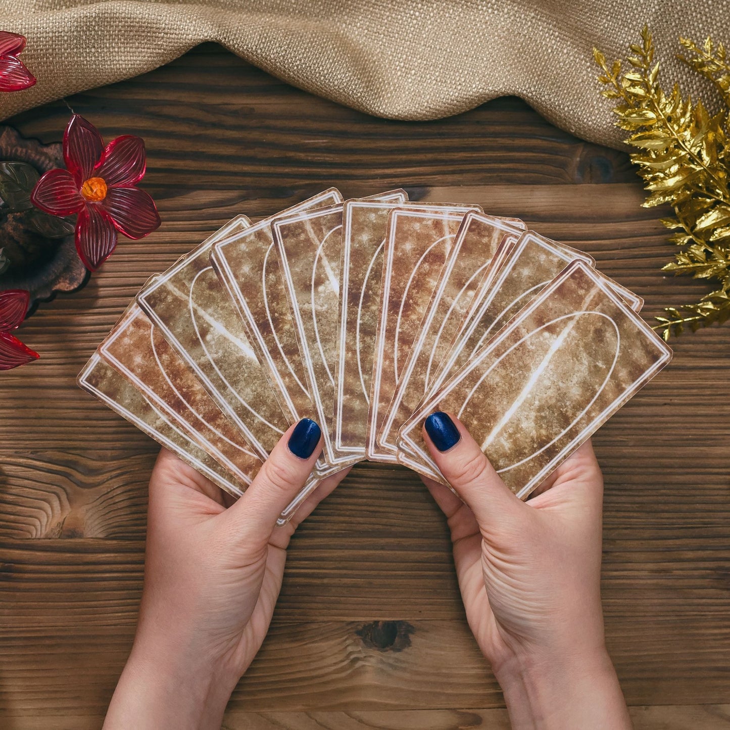 Hands holding brown tarot cards on wooden table.