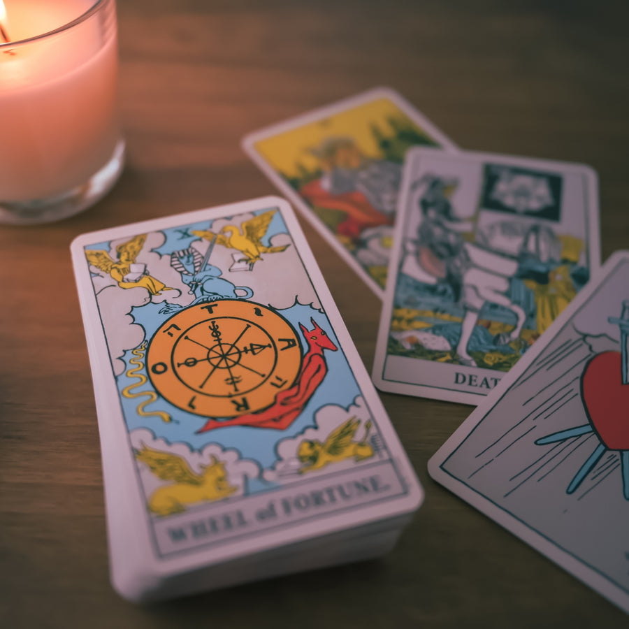 candle with tarot cards on wooden surface.
