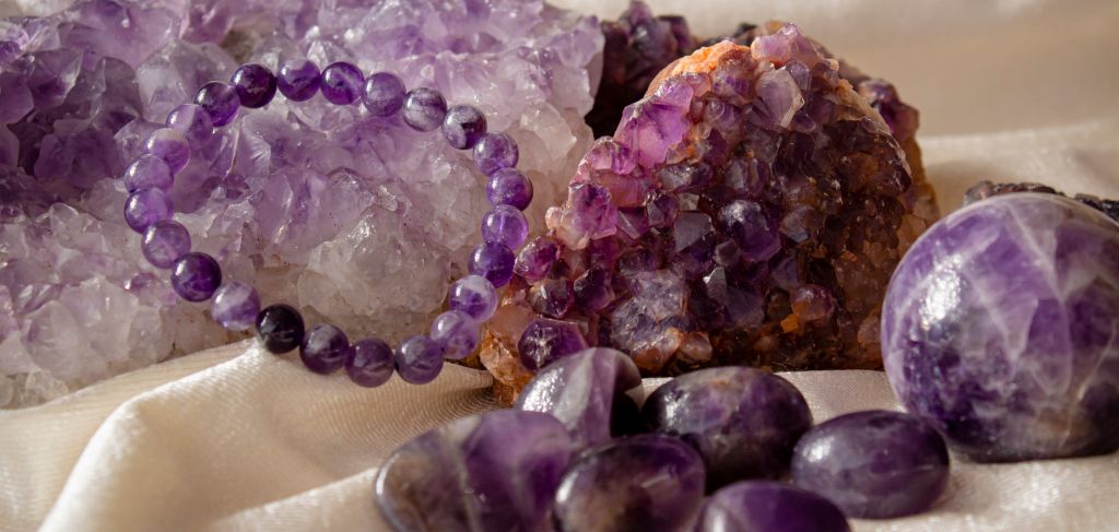 Amethyst cluster, geode, bracelet and tumbled stones styled on cream silk