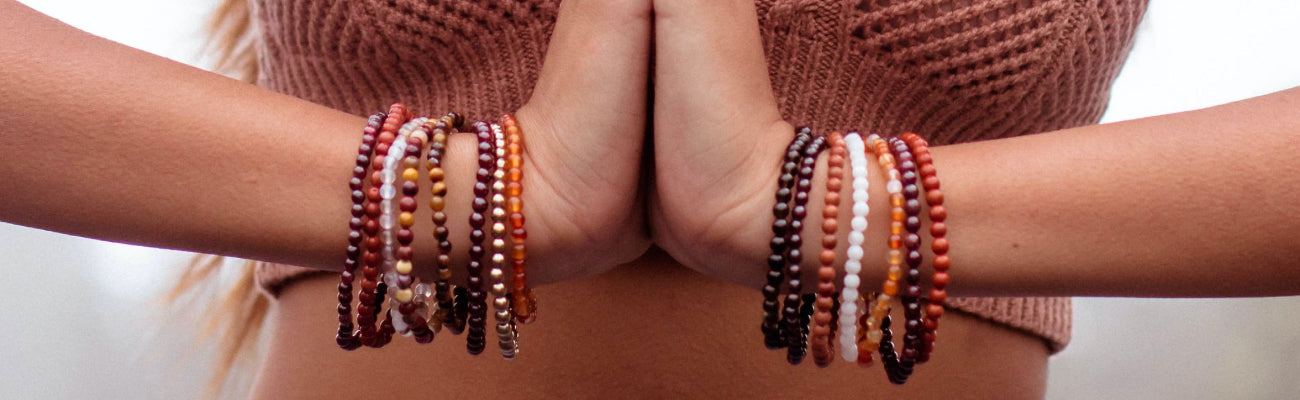 Layered crystal bead bracelet stacks worn on both wrists