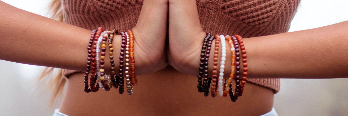 Stacked crystal bead bracelets worn on two wrists, Solacely Manifest collection