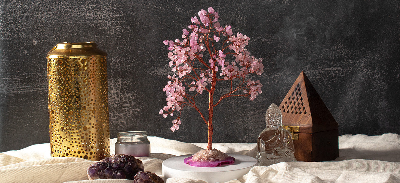 Styled shelf corner with a rose quartz crystal tree, brass lantern, amethyst geode and Buddha figure