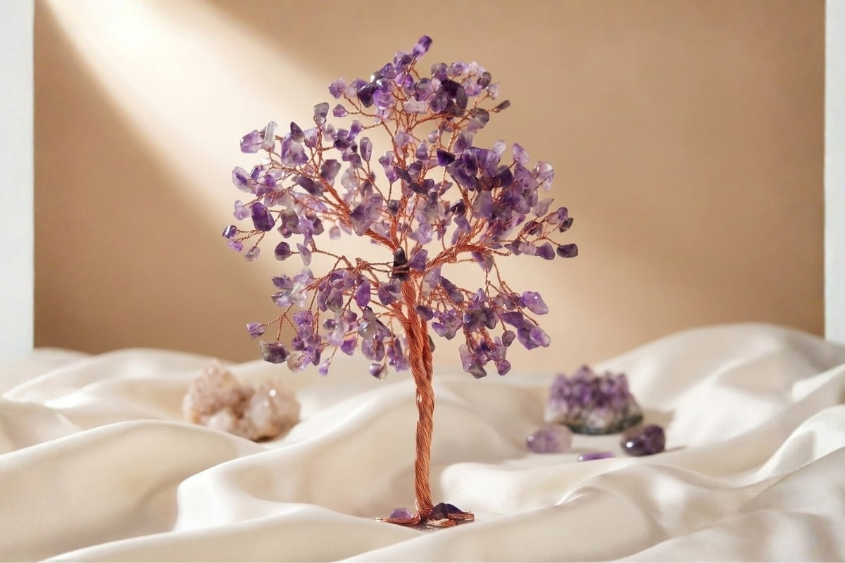 Rose quartz crystal tree styled on a shelf with a lantern and geode