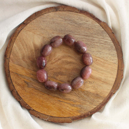 Strawberry Quartz Tumble Crystal Bracelet on round wooden base.