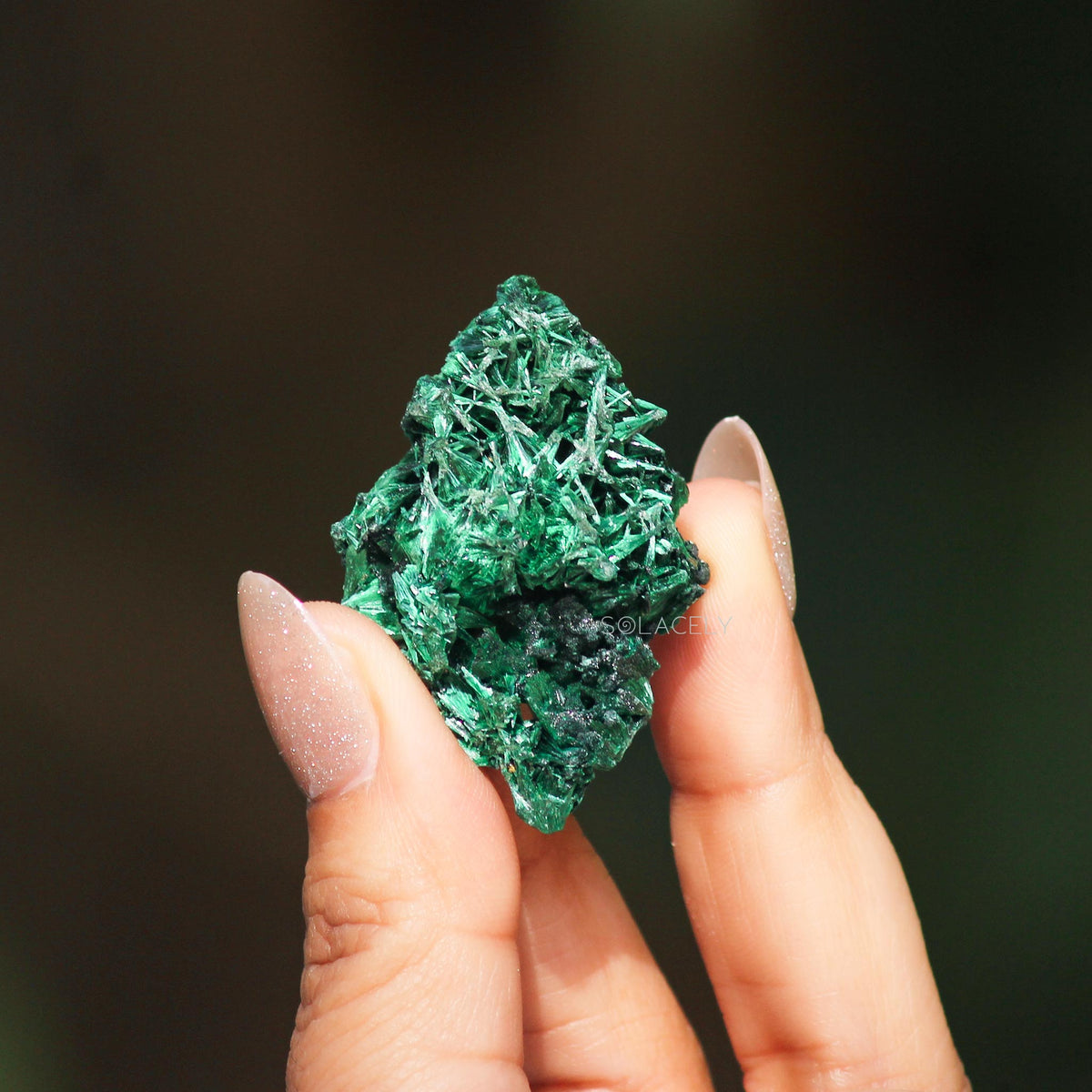 Textured malachite held by fingers