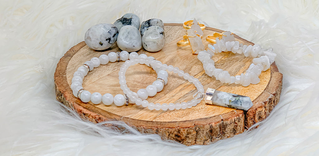 Moonstone bracelets, chip bracelet, rings and a pendant with tumbled moonstones on a wood slice