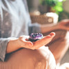 Person holding amethyst crystal in calm setting.