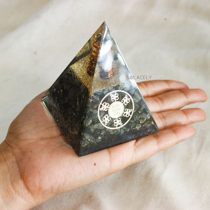 Hand holding a black and gold orgone pyramid with pyrite