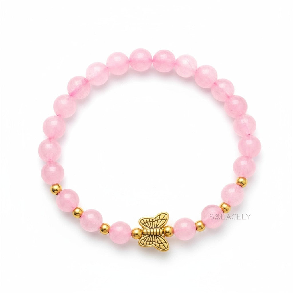 Rose quartz bracelet with a gold butterfly charm at the wrist
