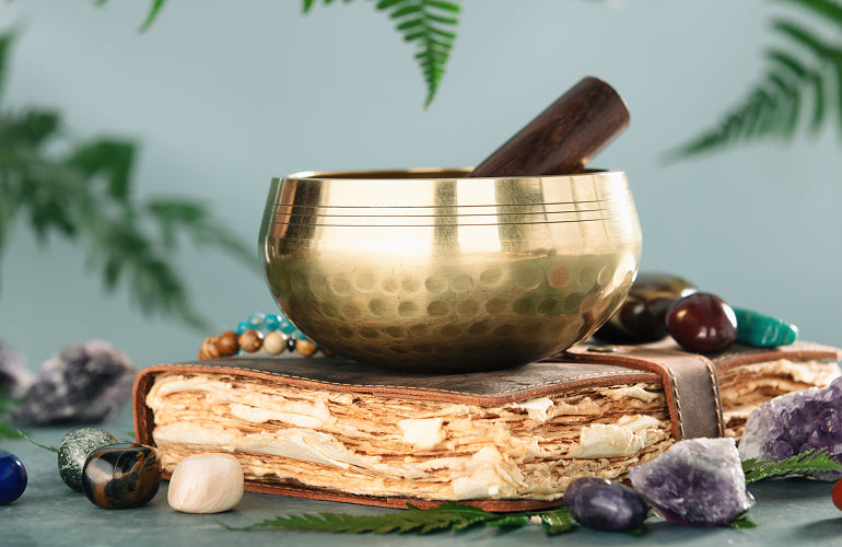 Singing bowl resting on an antique book, surrounded by crystals
