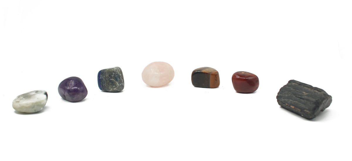 Row of seven chakra tumbled stones on a white background